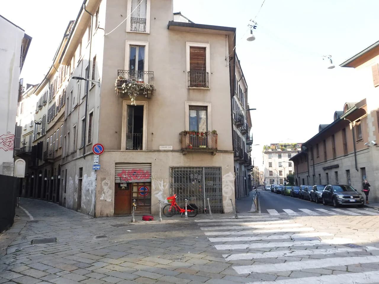 An old townhouse with iron balconies at a quiet cobbled junction in the Cinque Vie quarter of central Milan