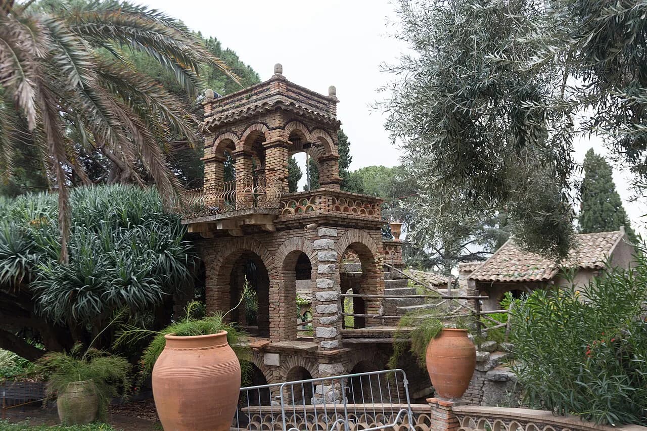 Ornate stone folly, palms and terracotta urns in the Villa Comunale gardens of Taormina, Sicily