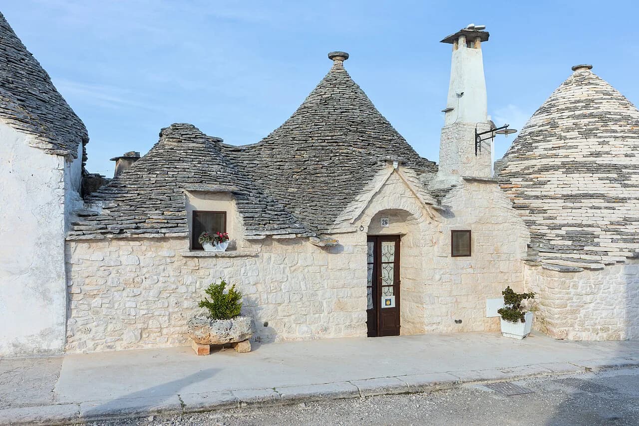 Whitewashed trulli with conical stone roofs on a quiet lane in Rione Aia Piccola, Alberobello