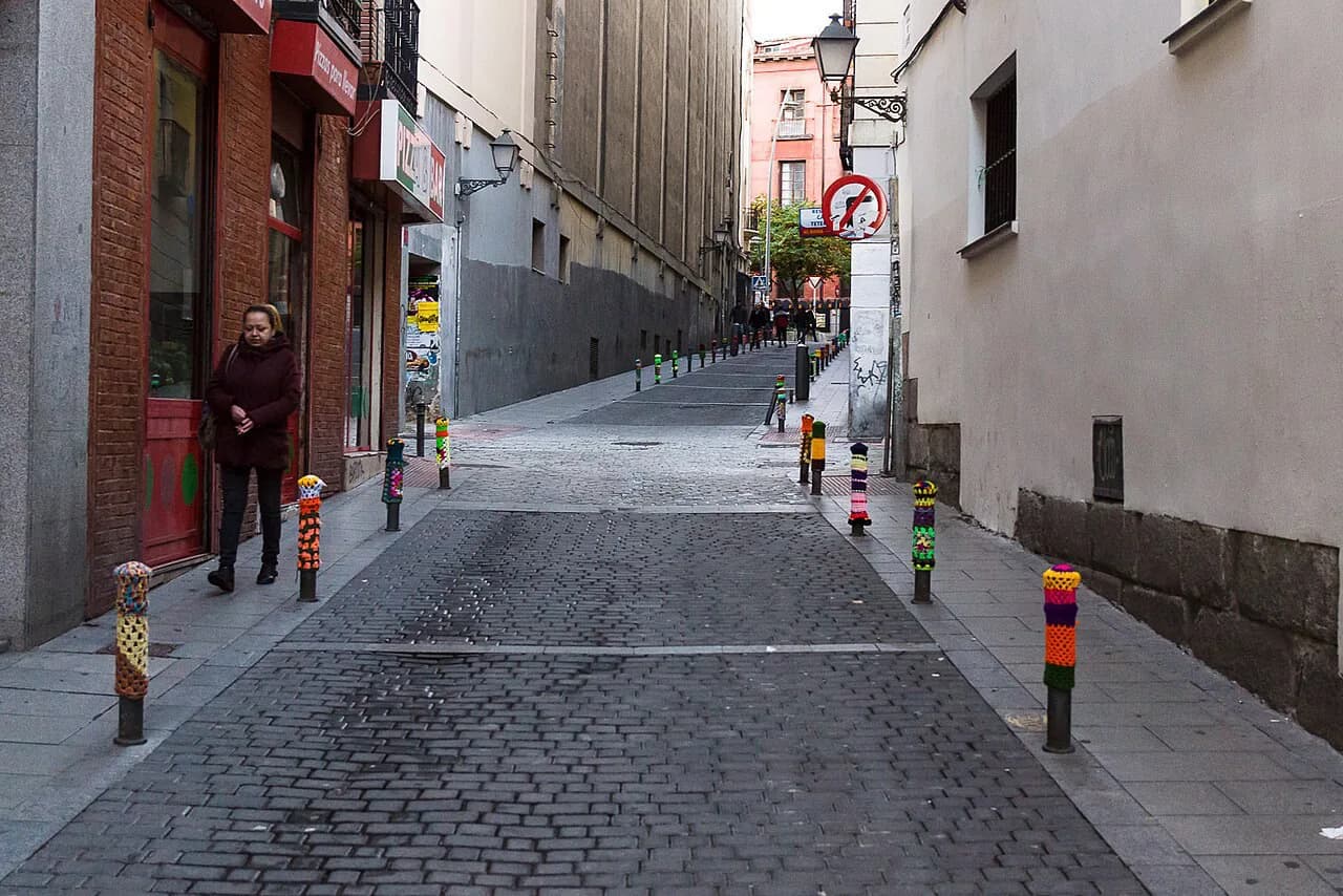 Narrow cobbled Calle de Lavapiés sloping uphill between old apartment buildings in Madrid