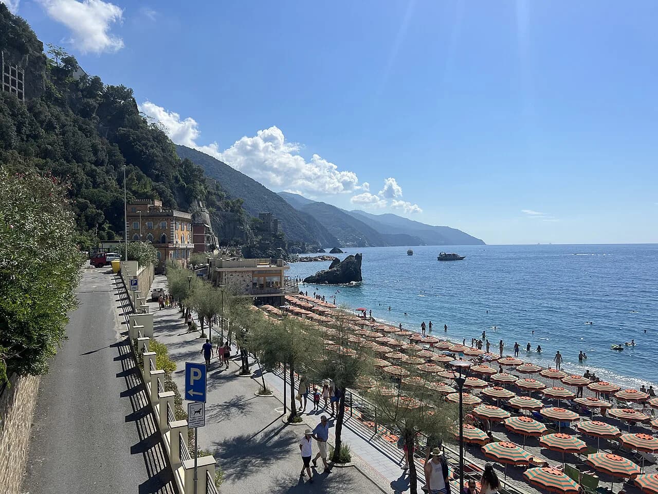Fegina seafront road and promenade in Monterosso al Mare above rows of beach umbrellas and the sea