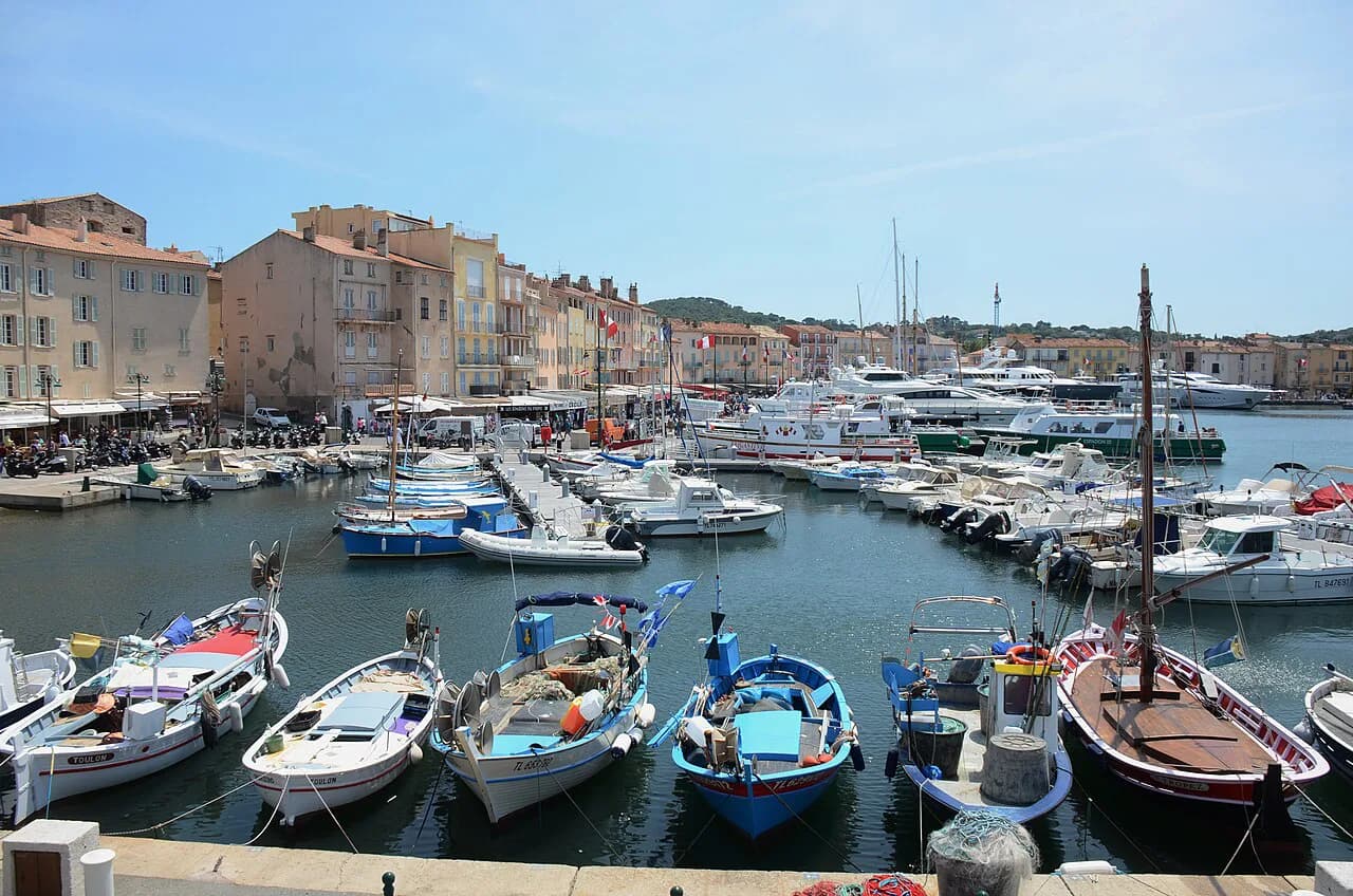 Small boats moored in the Old Port of Saint-Tropez in front of pastel-coloured harbourfront houses
