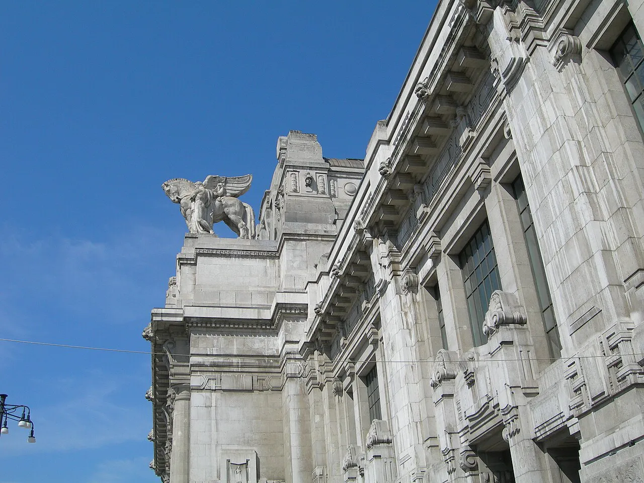 Winged-horse sculpture and carved stone walls on the facade of Milano Centrale station