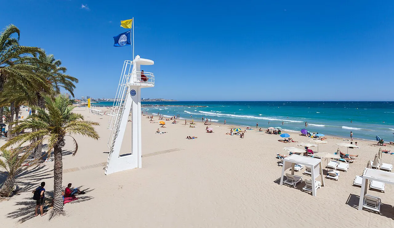 White lifeguard tower and palm trees on the sand of Postiguet Beach in Alicante