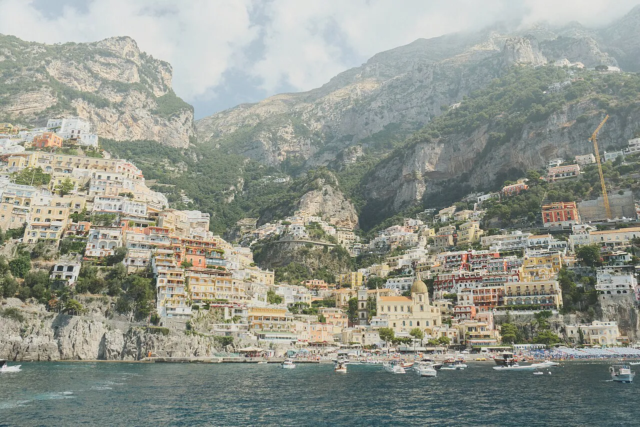 Positano's pastel houses spilling down to the bay beneath steep mountains, seen from the sea