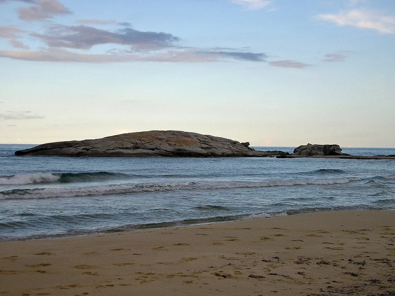 The low rocky islet of Scoglio di Peppino off the sandy beach at Costa Rei in soft evening light