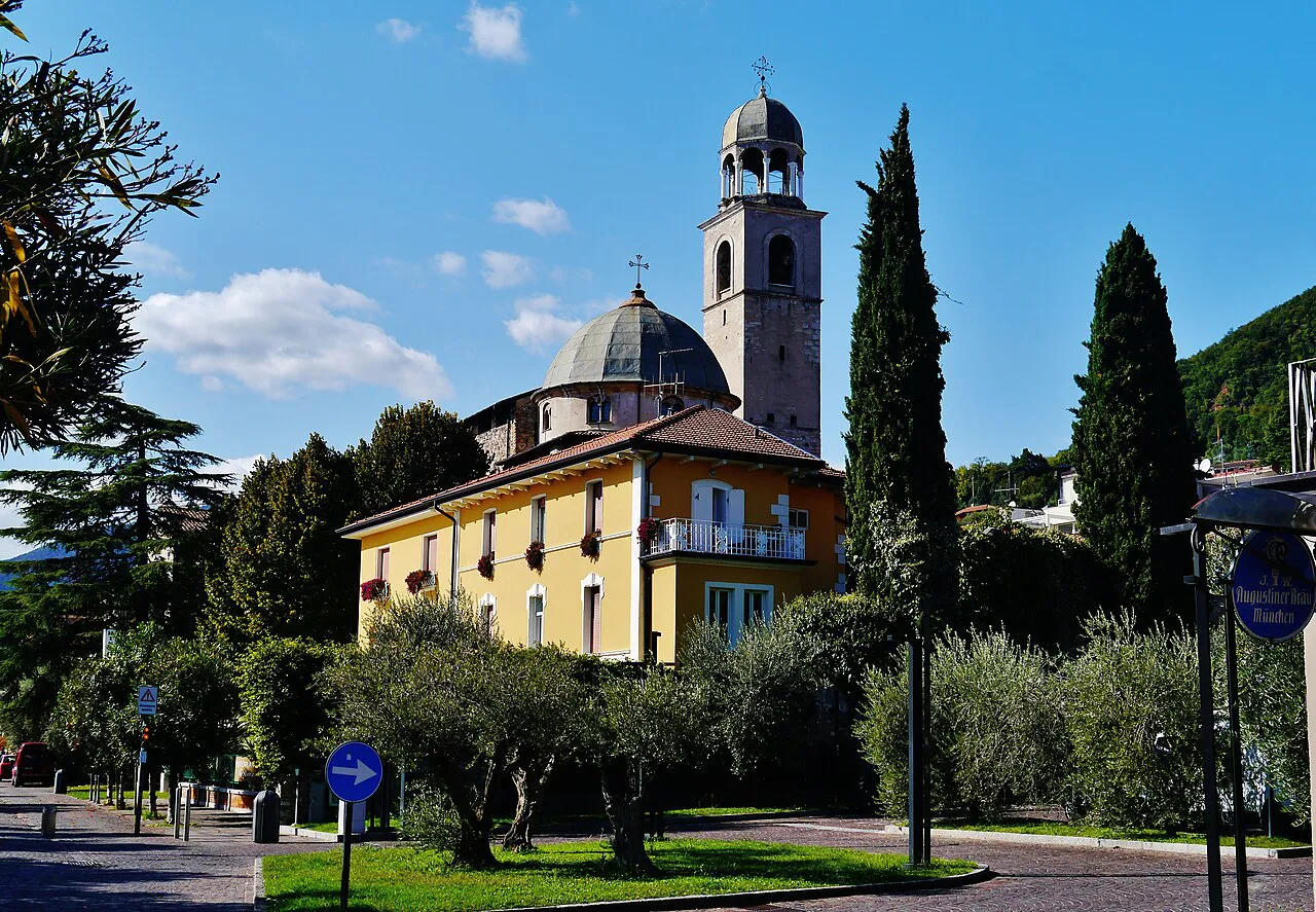 Domed church and bell tower behind cypresses and olive trees on Lungolago Zanardelli in Salò, Lake Garda