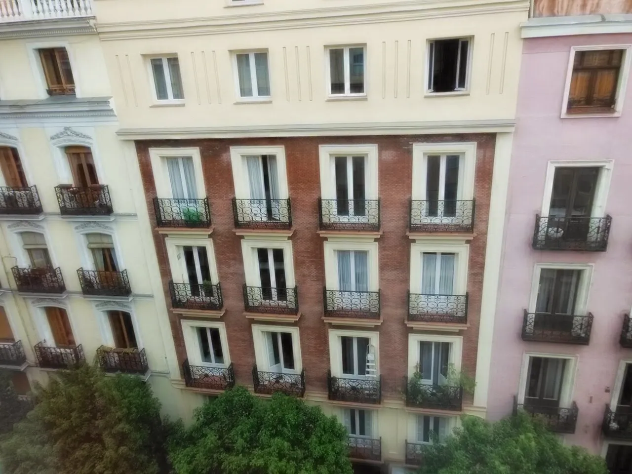 Pastel and brick apartment façades with iron balconies on Calle de Manuela Malasaña in Madrid