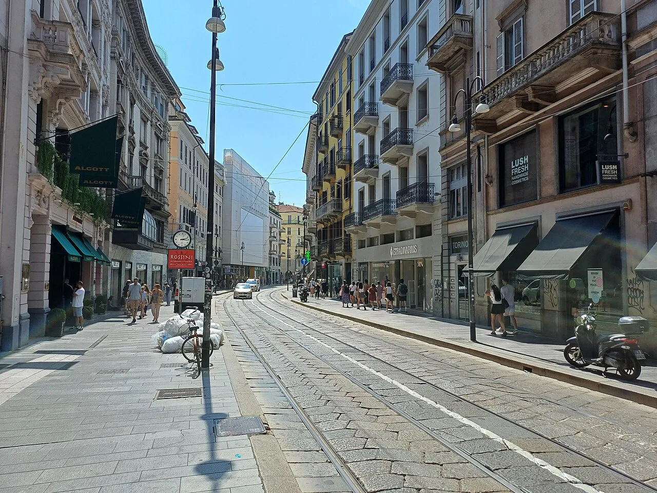 Via Torino in Milan, a straight shopping street with tram tracks and tall apartment facades