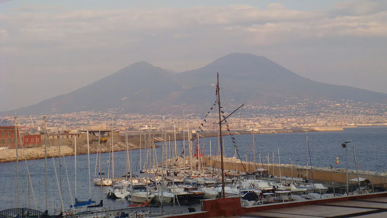 Mount Vesuvius rising beyond a marina of sailing boats on the Naples waterfront
