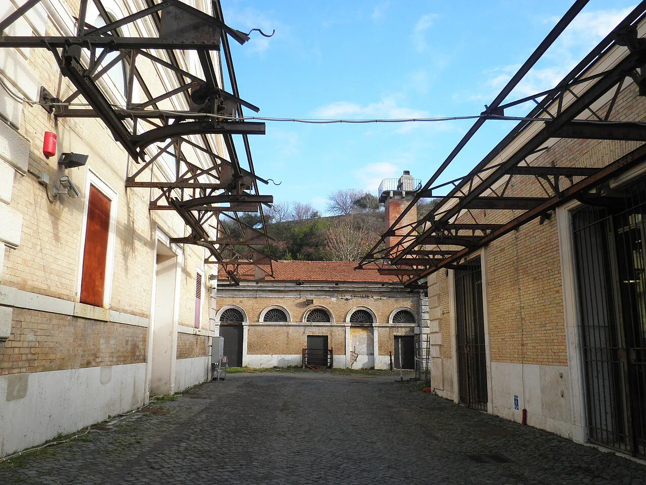 Cobbled courtyard of the former Mattatoio slaughterhouse complex in Testaccio, Rome, with iron roof frames