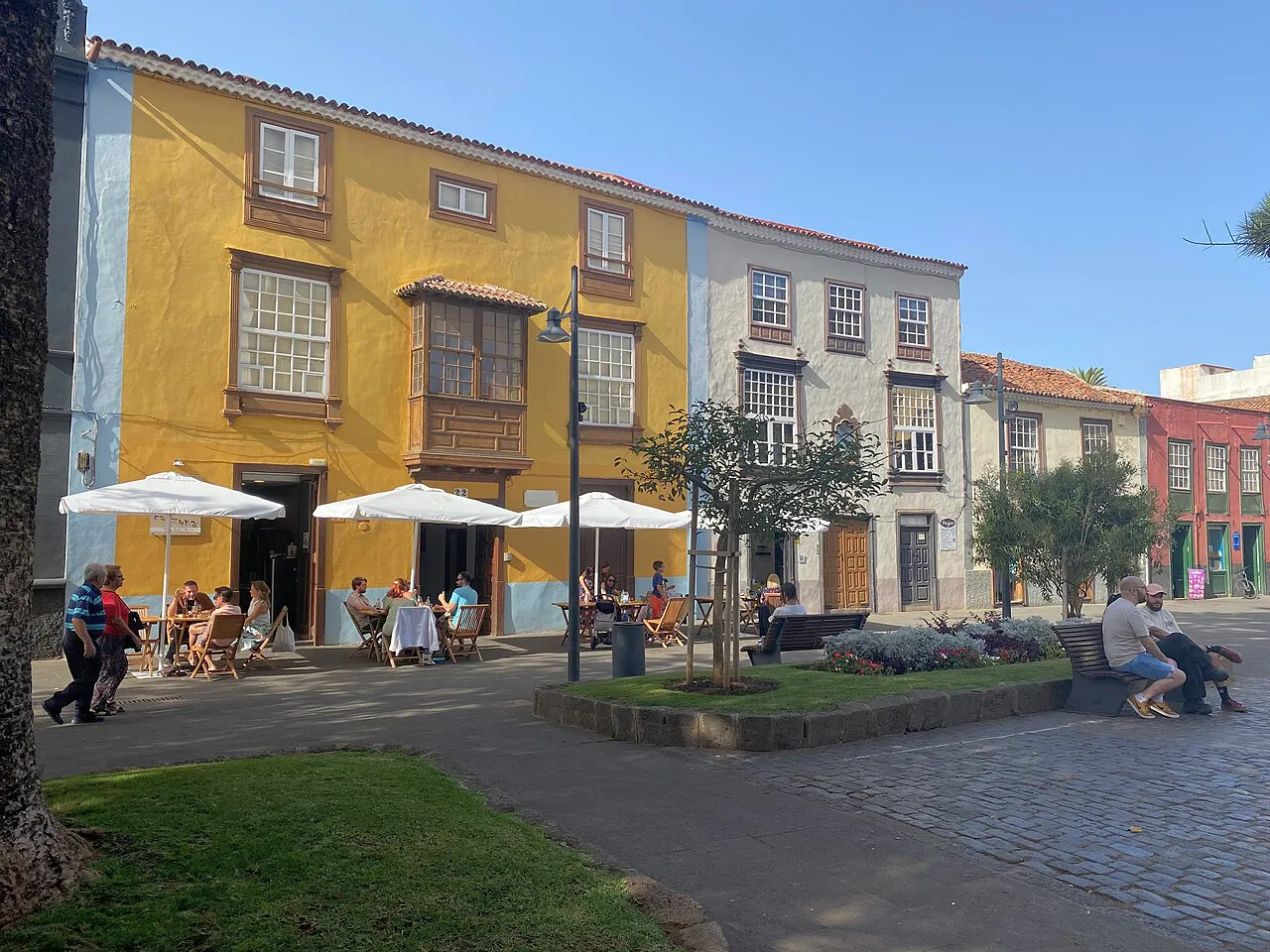 Café terraces under white umbrellas outside colourful historic houses on Plaza de la Concepción, La Laguna