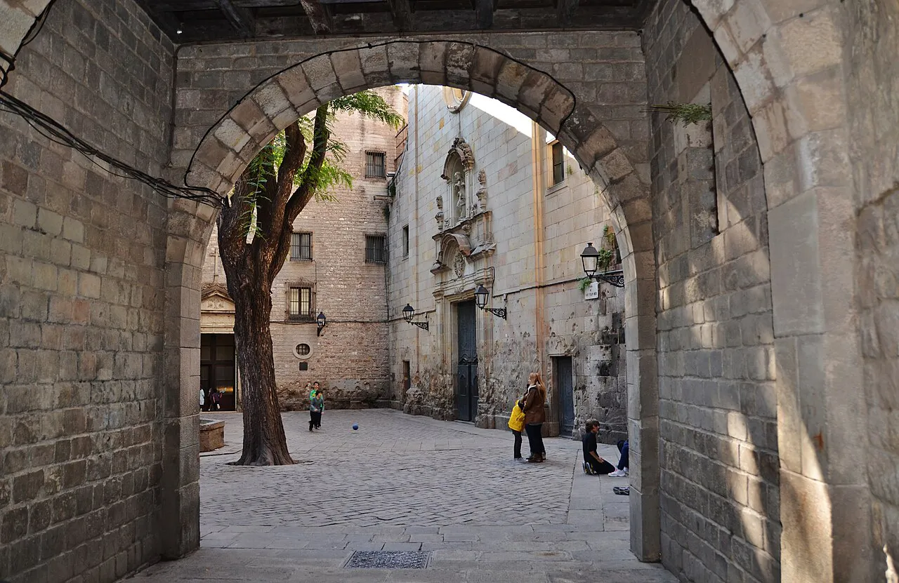 Stone archway opening onto the quiet cobbled Plaça de Sant Felip Neri in Barcelona's Gothic Quarter