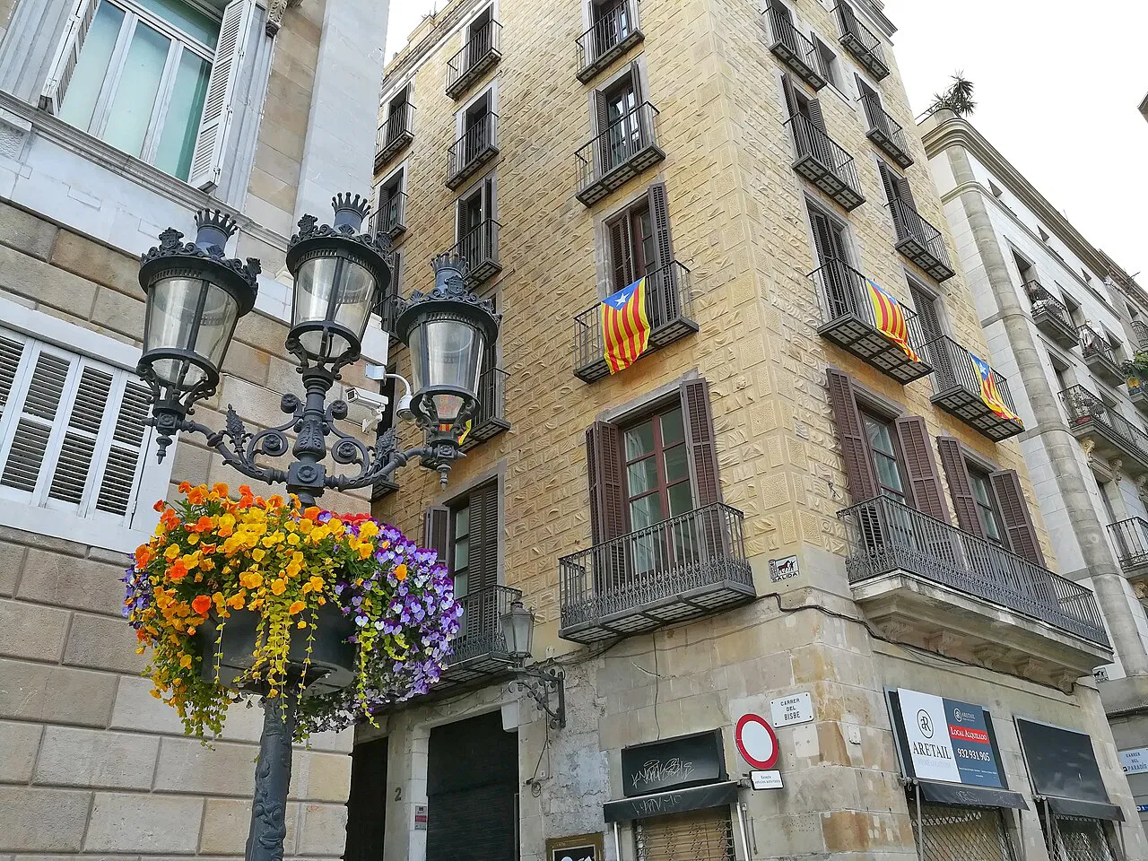 Flower-filled lamp post and old balconied buildings beside Plaça de Sant Jaume in the Gothic Quarter, Barcelona