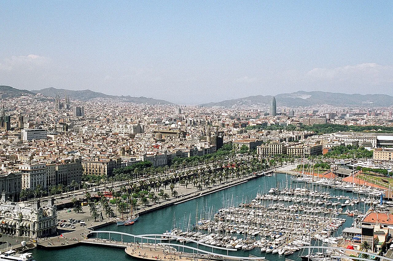 Aerial view of the Port Vell marina, waterfront promenade and city behind it in Barcelona