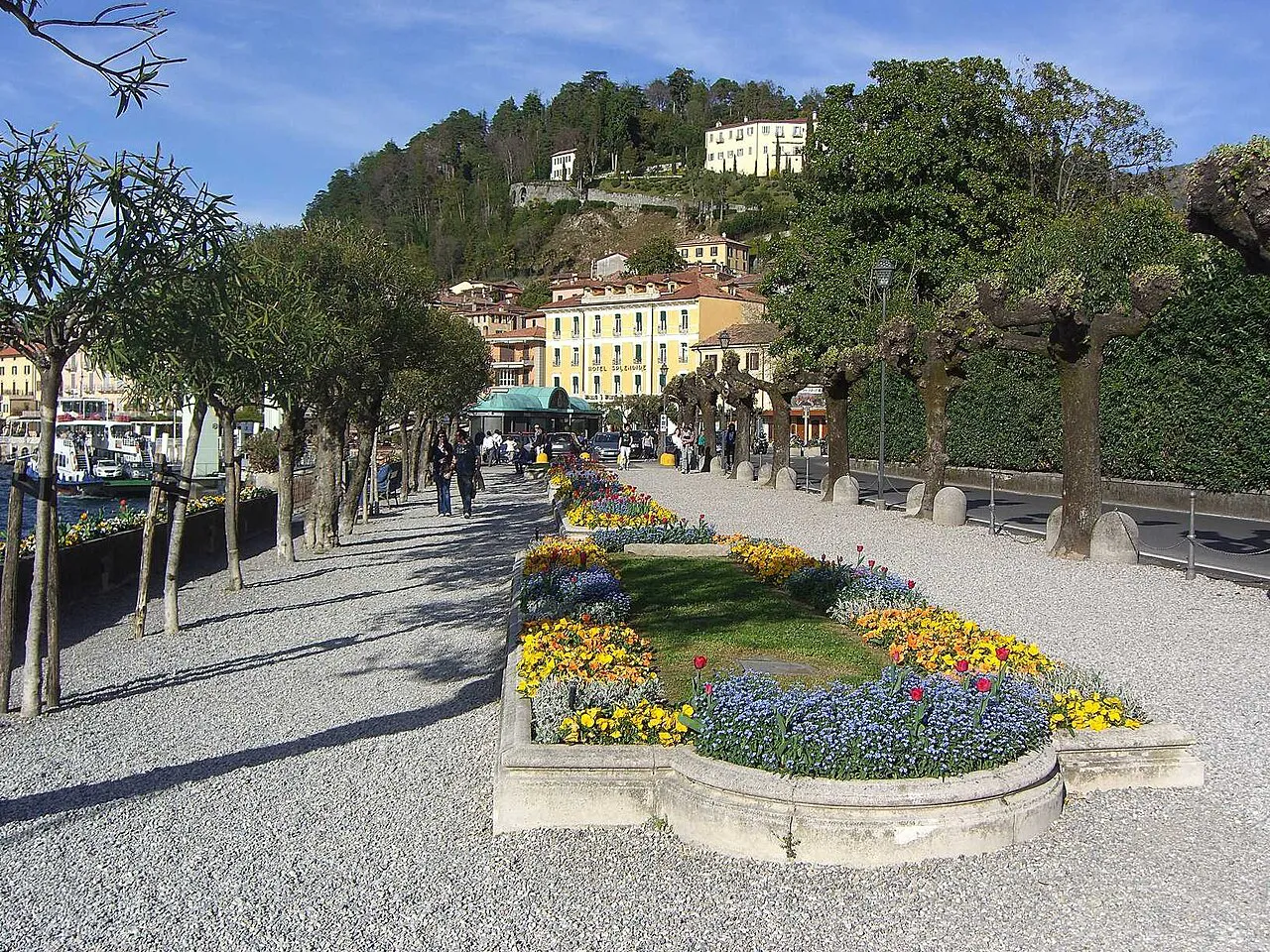 Flowerbeds and tree-lined gravel promenade along the lakefront gardens in Bellagio, Lake Como