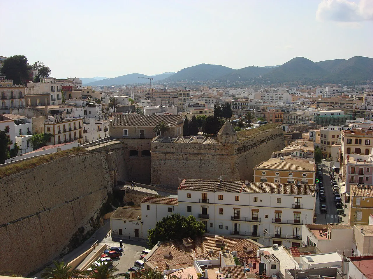 Dalt Vila's stone ramparts above the rooftops of Ibiza Town, with hills on the horizon