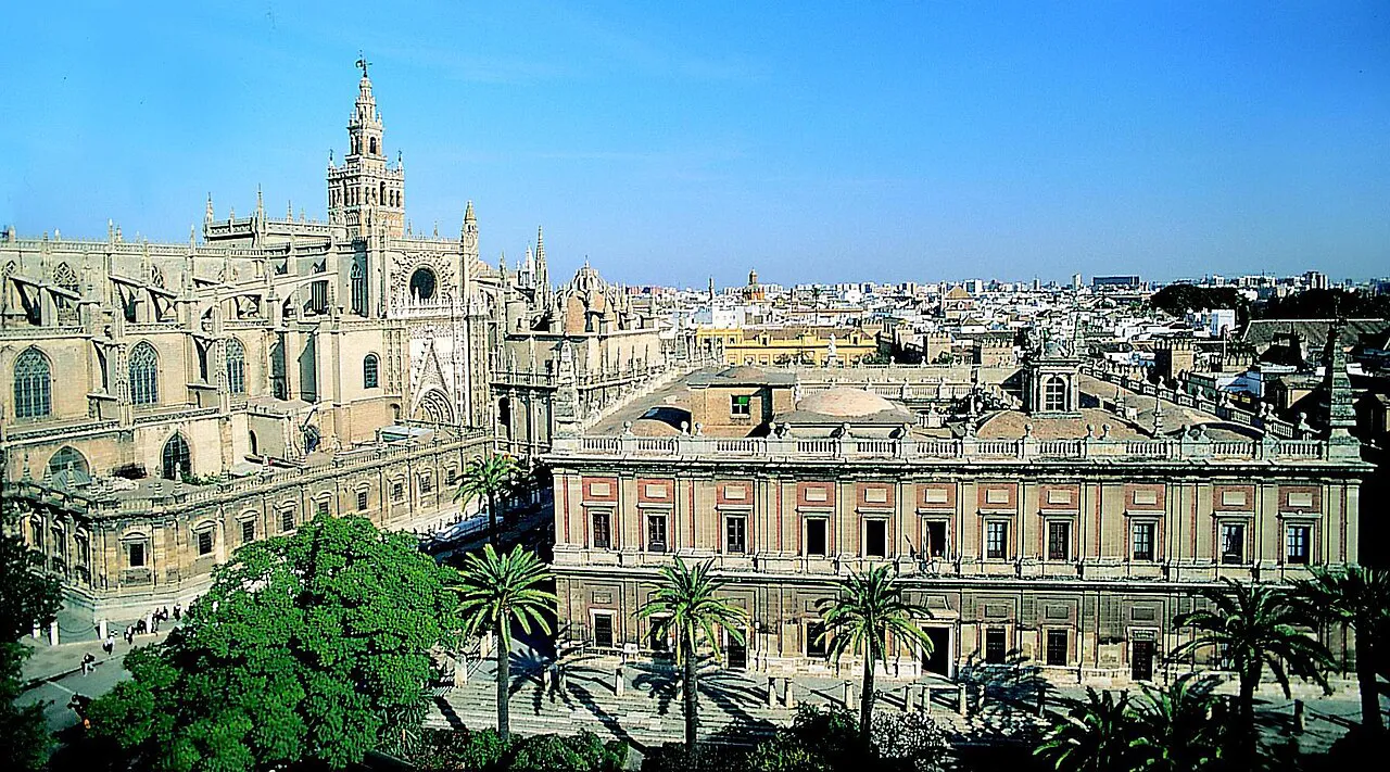 Seville Cathedral and the Giralda beside the Archivo de Indias, seen from above with palms in the foreground