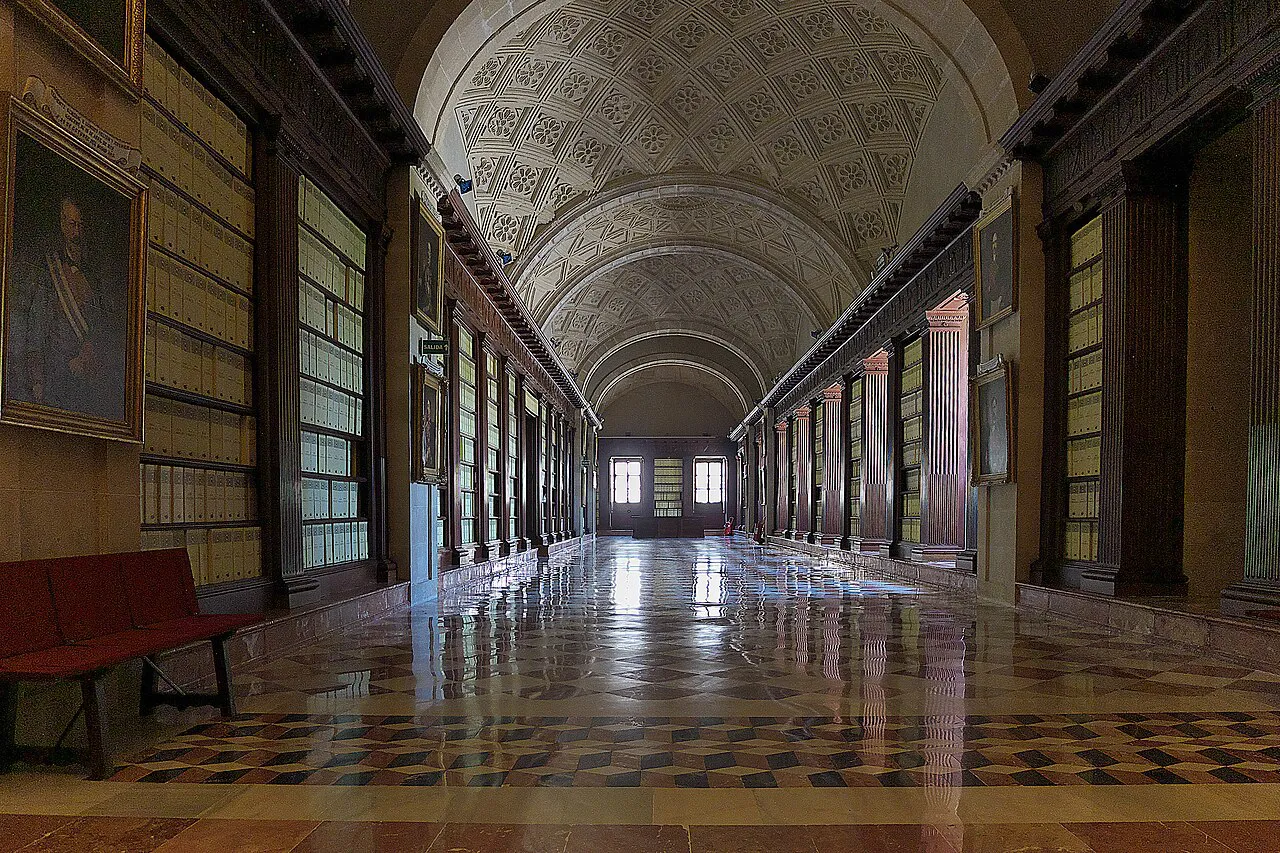 The long vaulted gallery of the Archivo General de Indias with polished marble floor and wooden shelving, Seville