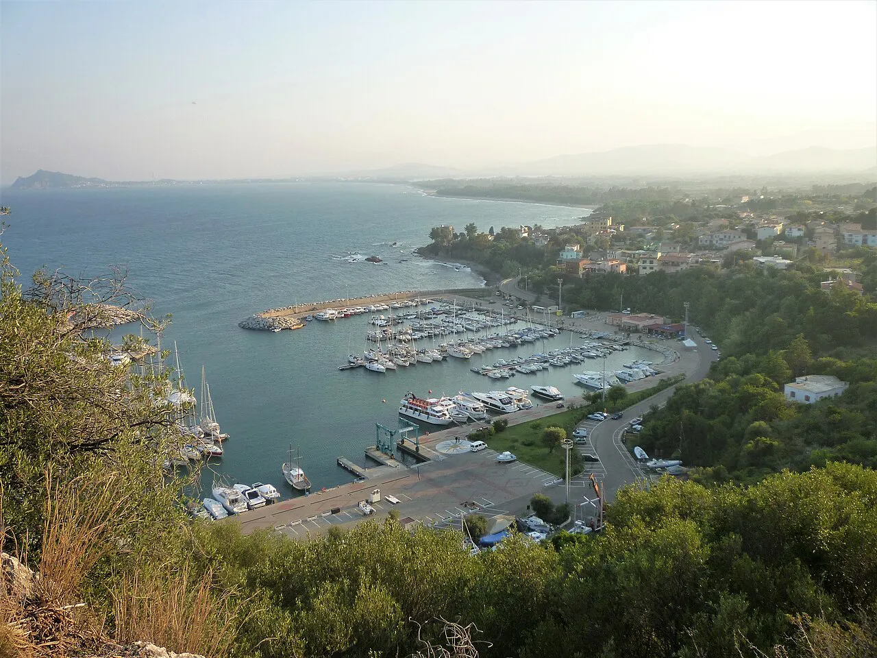 View over the small harbour of Santa Maria Navarrese with boats and the wooded coast beyond