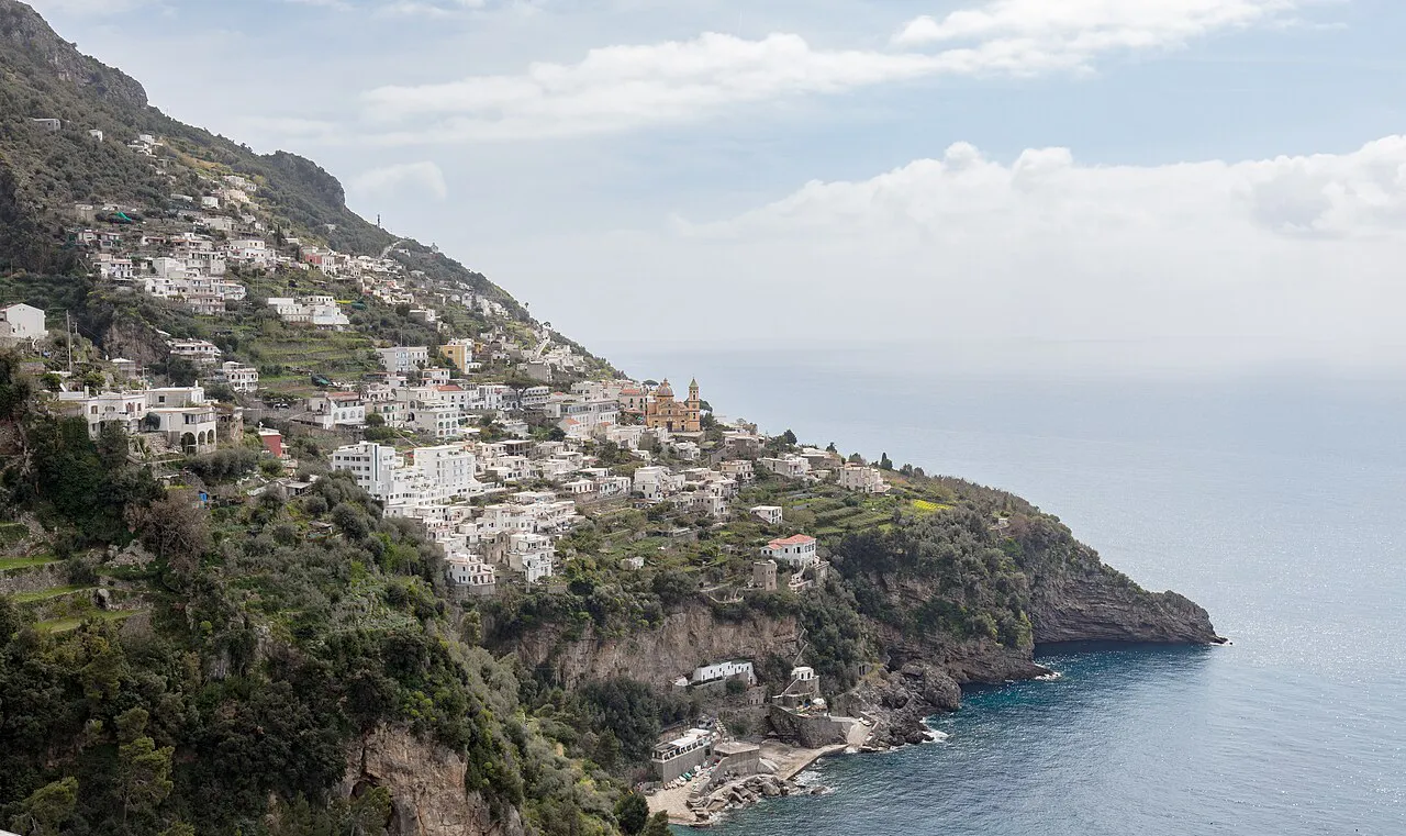 White houses of Praiano spread across green terraced slopes above the sea on the Amalfi Coast