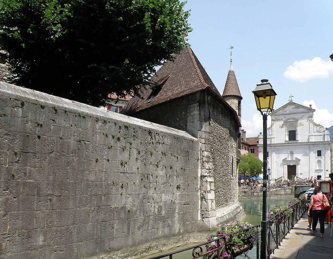 Stone wall of the Palais de l'Isle with the white facade of the Saint-François church beyond, Annecy