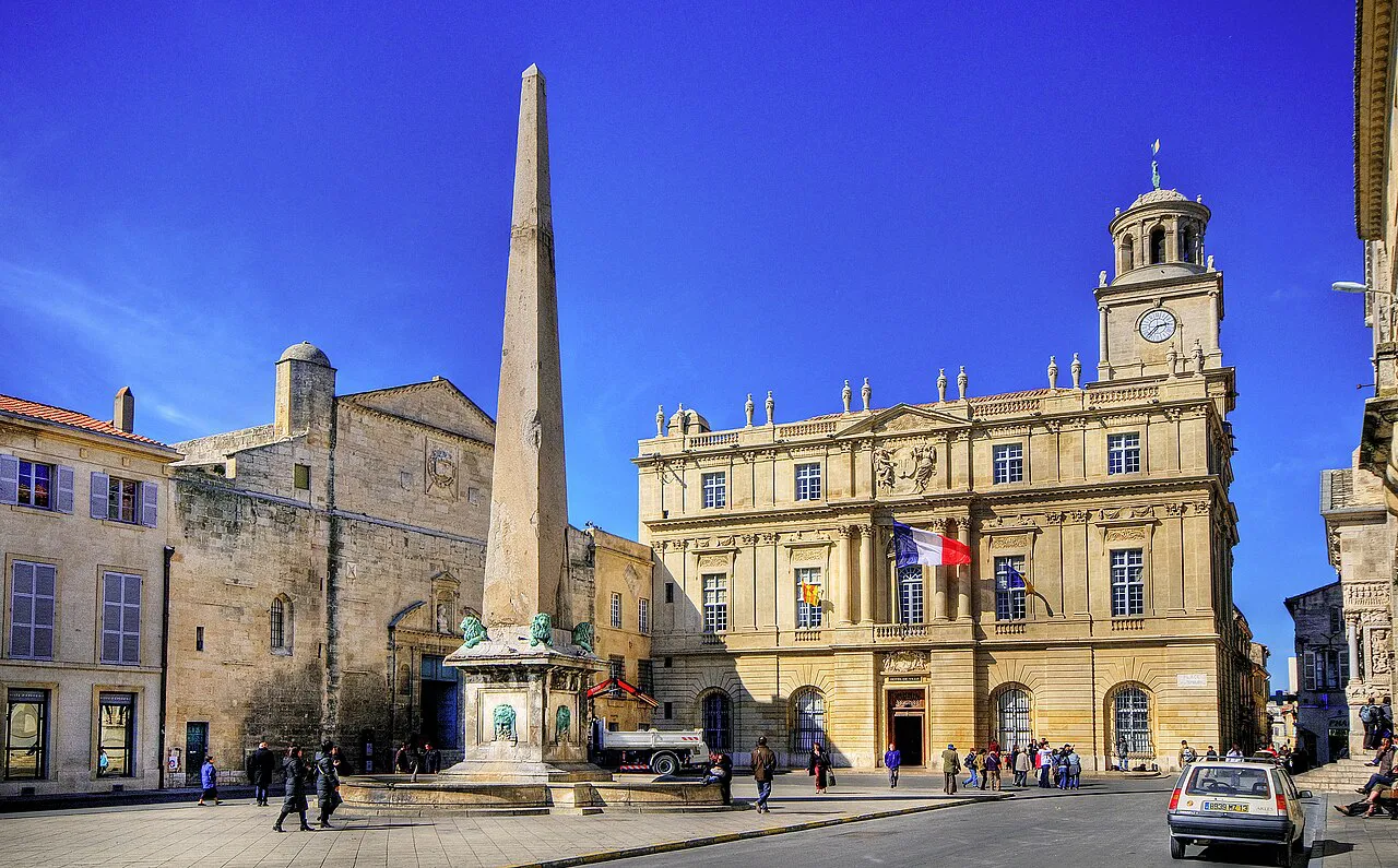 Place de la République in Arles with the Roman obelisk and the classical town hall under a deep blue sky
