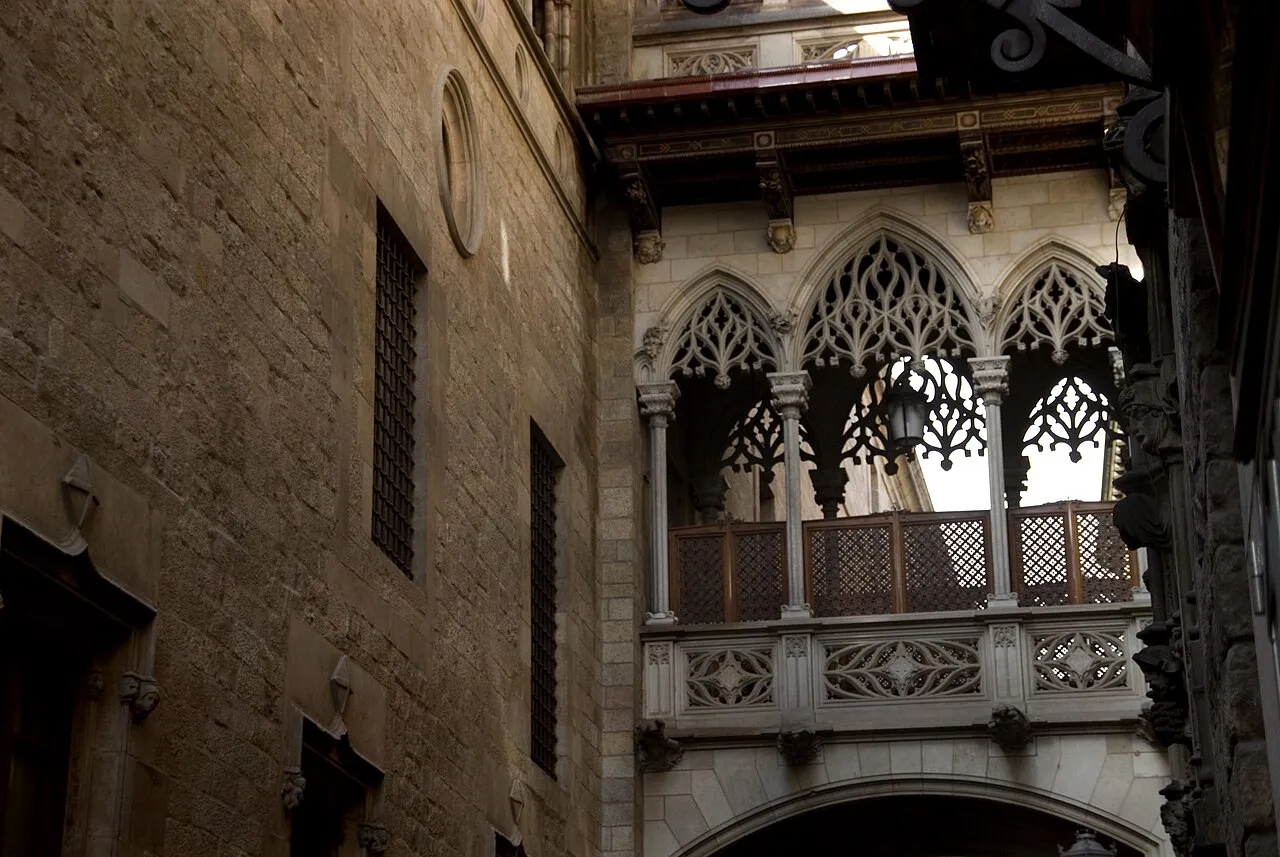 Neo-Gothic carved stone bridge spanning narrow Carrer del Bisbe in Barcelona's Gothic Quarter