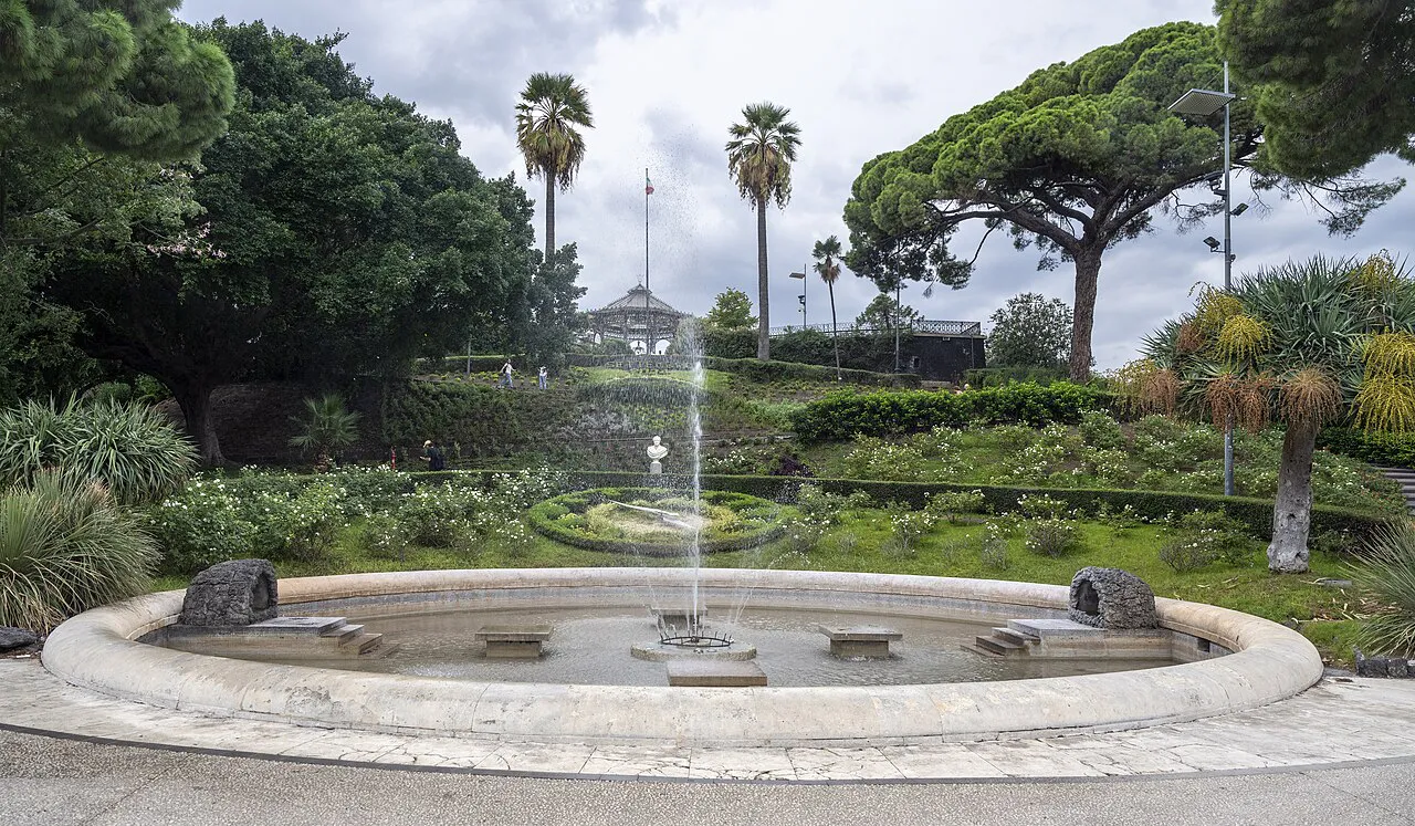 Round fountain among palms and flower beds at the entrance of the Villa Bellini garden in Catania