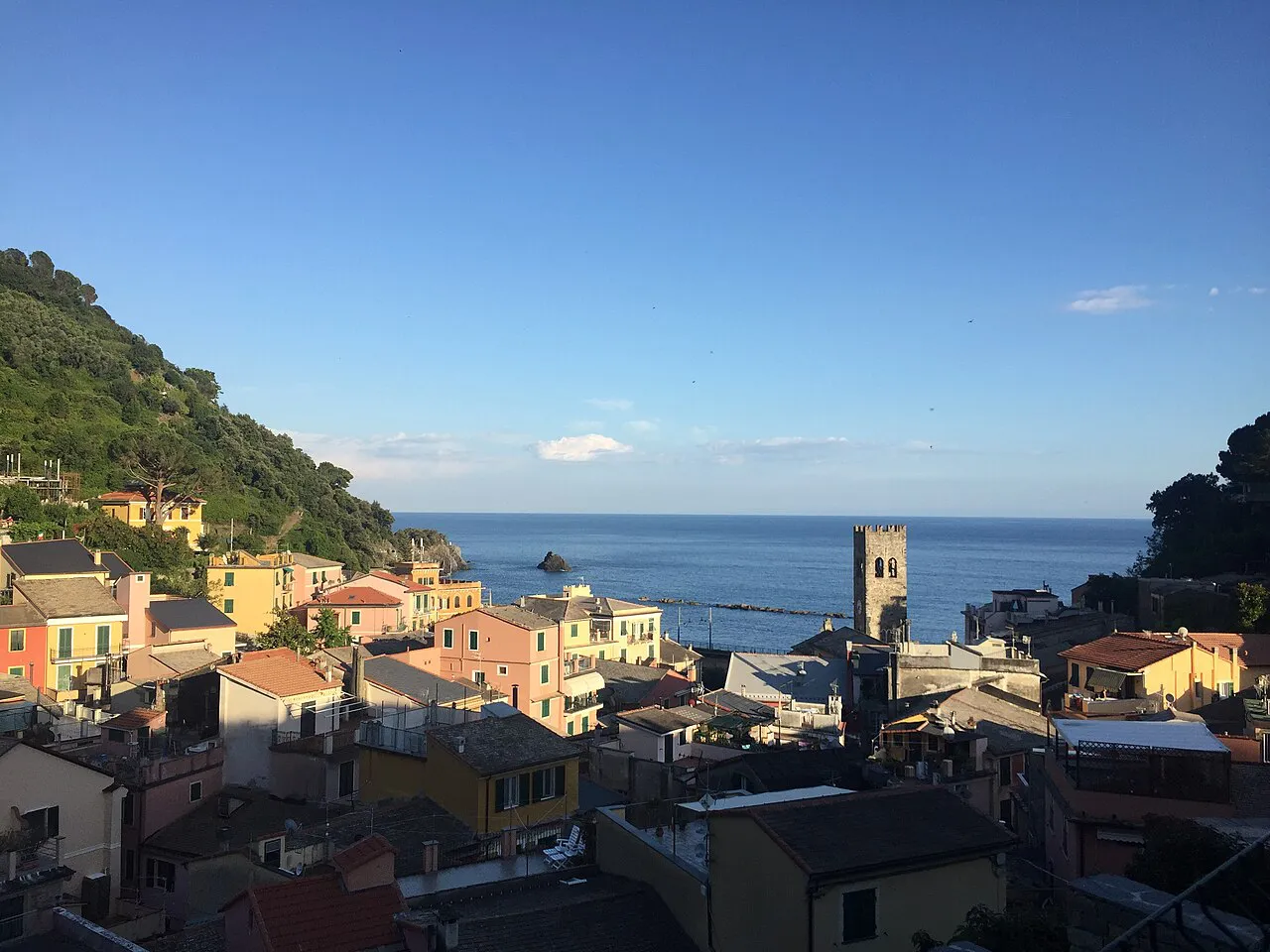 Old-town rooftops and a stone bell tower of Monterosso al Mare with the sea beyond