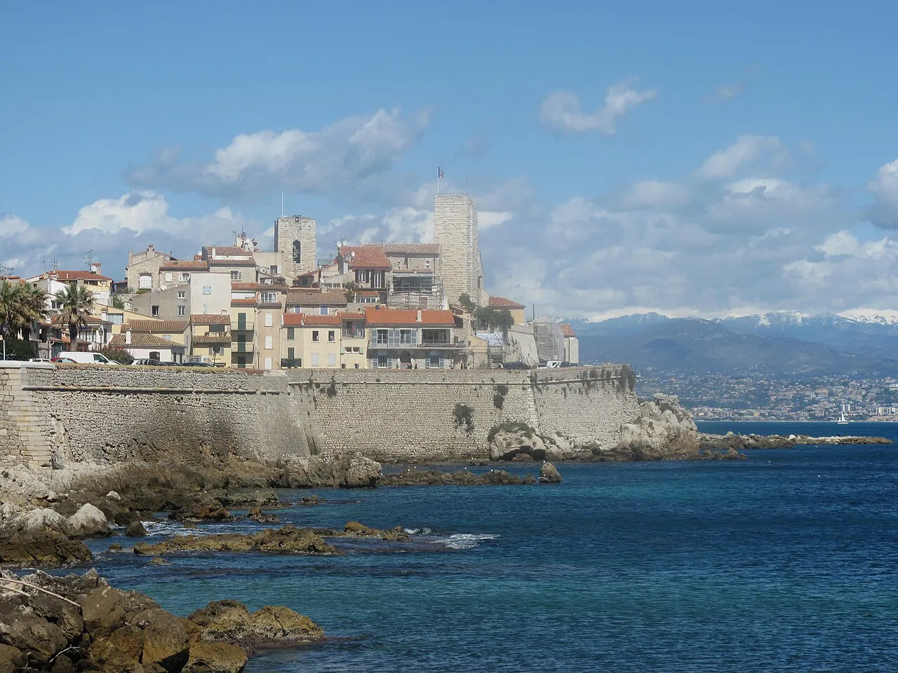 Old town of Antibes rising above its seawalls, with the snow-capped Alps on the horizon