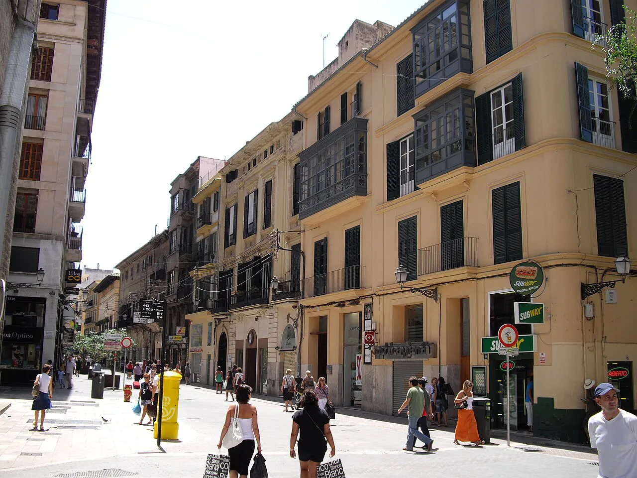 Ochre townhouses with enclosed balconies lining a pedestrian street in central Palma