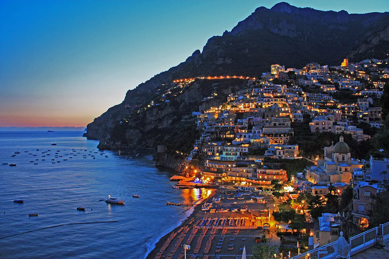 Positano's hillside lit up at dusk above the bay and the main beach