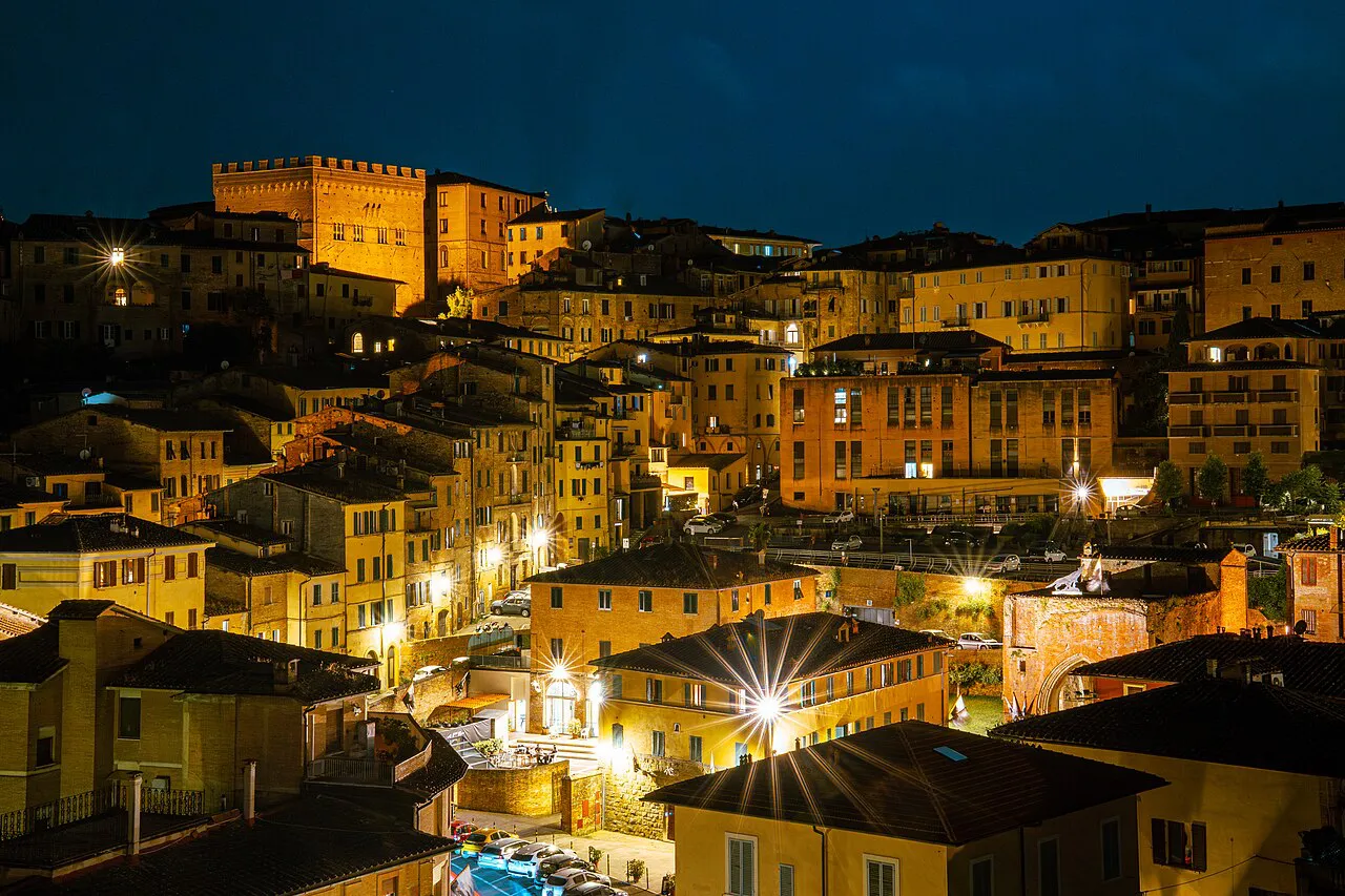 Golden lights glowing on the stacked houses of Siena's old town at night