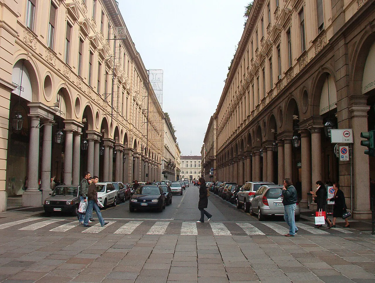 Symmetrical stone arcades lining both sides of Via Roma in central Turin