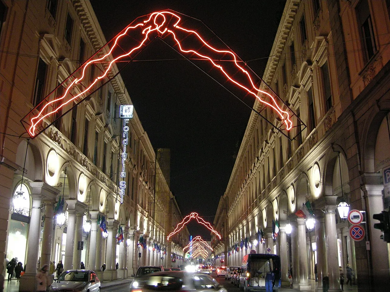 Via Roma in Turin at night, its lit arcades spanned by a neon light-art installation