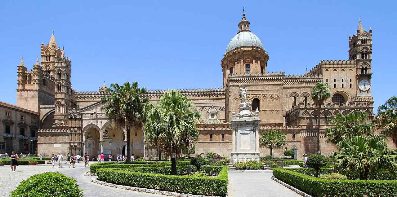 Palermo Cathedral with its domes, towers and palm-planted garden on a sunny day