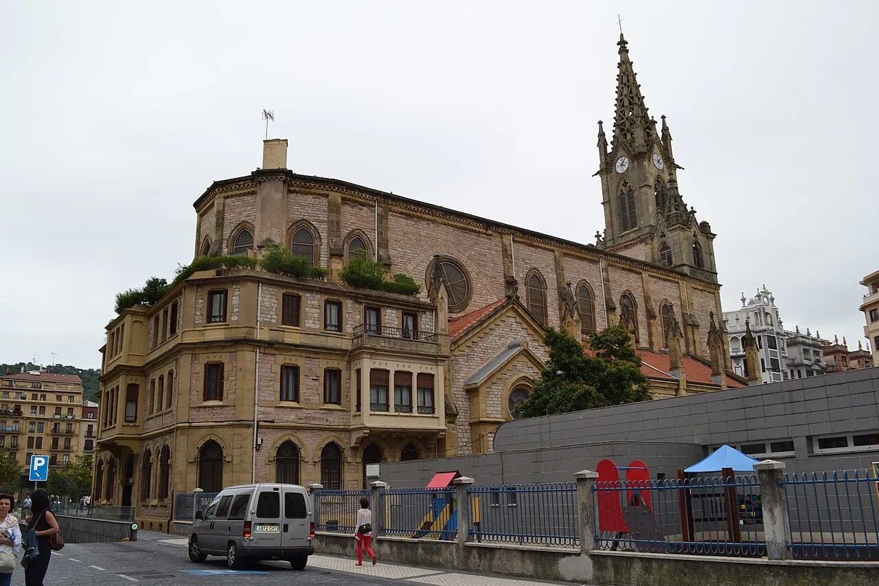 The neo-Gothic spire of the Buen Pastor Cathedral rising behind stone buildings in central San Sebastián