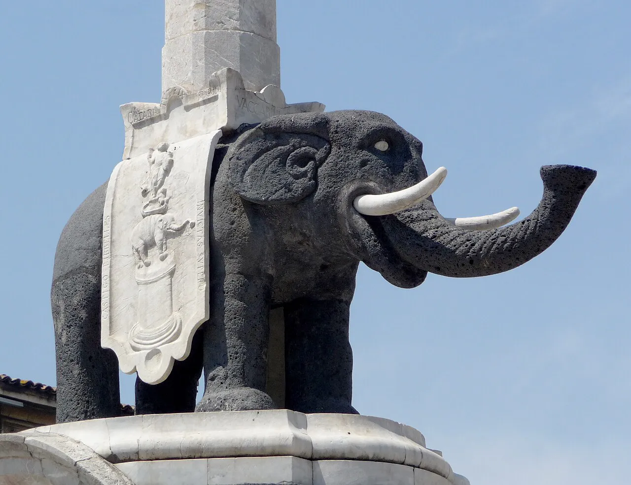 Close view of the black lava-stone elephant of the Fontana dell'Elefante in Catania against a blue sky
