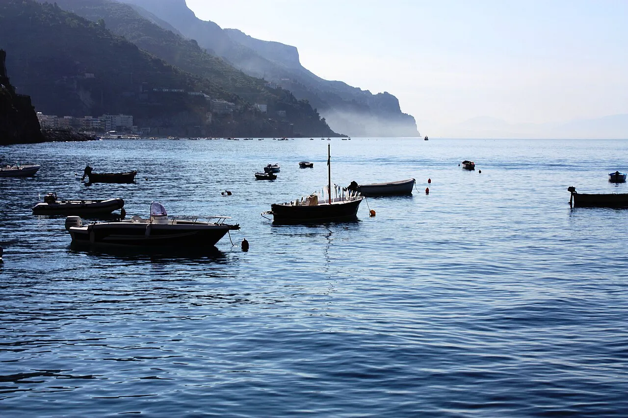 Small fishing boats moored in calm water off Minori beneath the Amalfi Coast cliffs