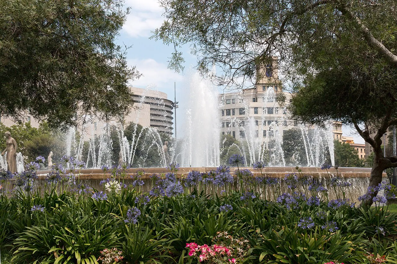 Fountain and flower beds framed by trees in Plaça de Catalunya, central Barcelona