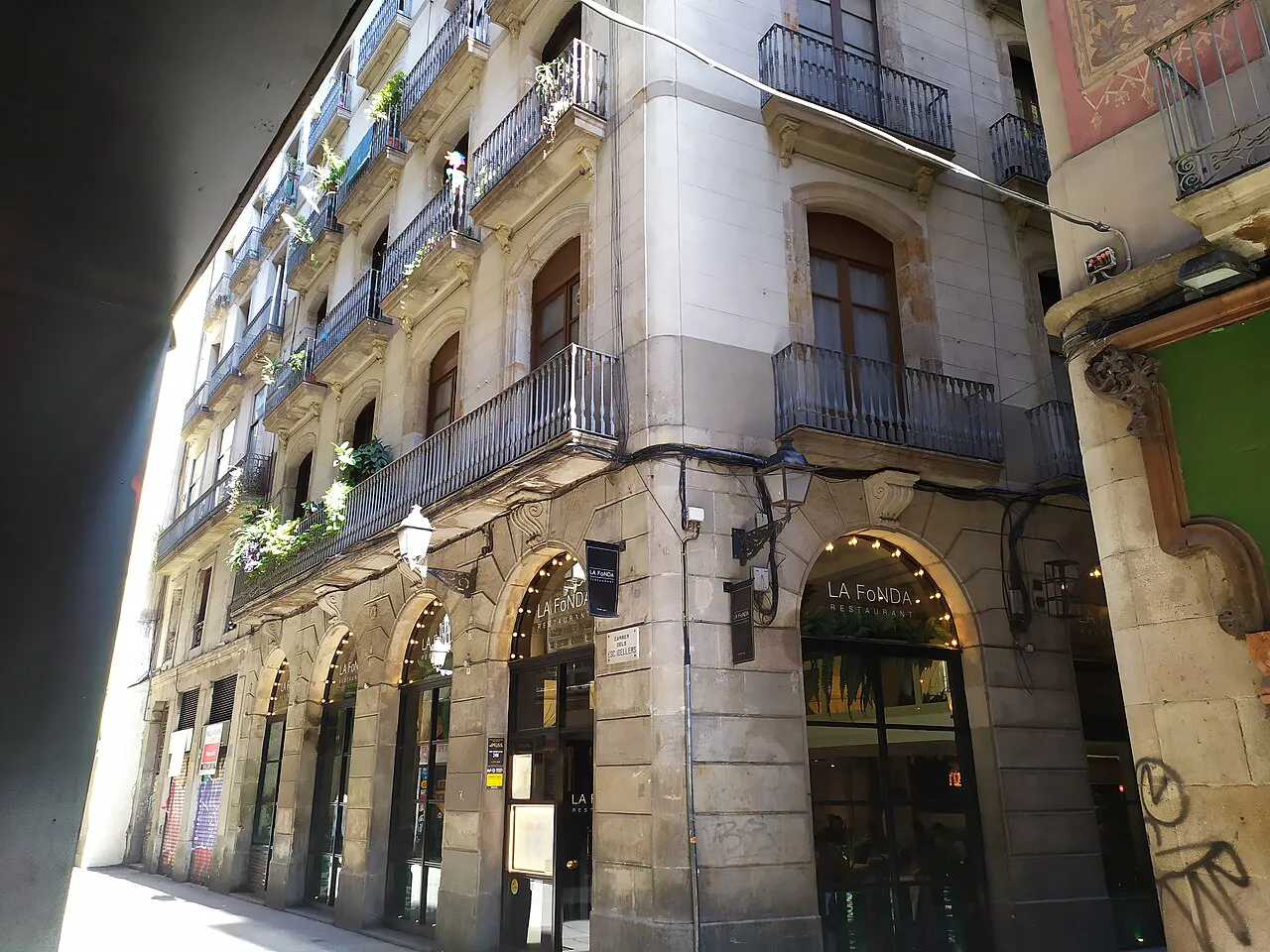 Arcaded stone building with iron balconies on narrow Carrer dels Escudellers in Barcelona's old town