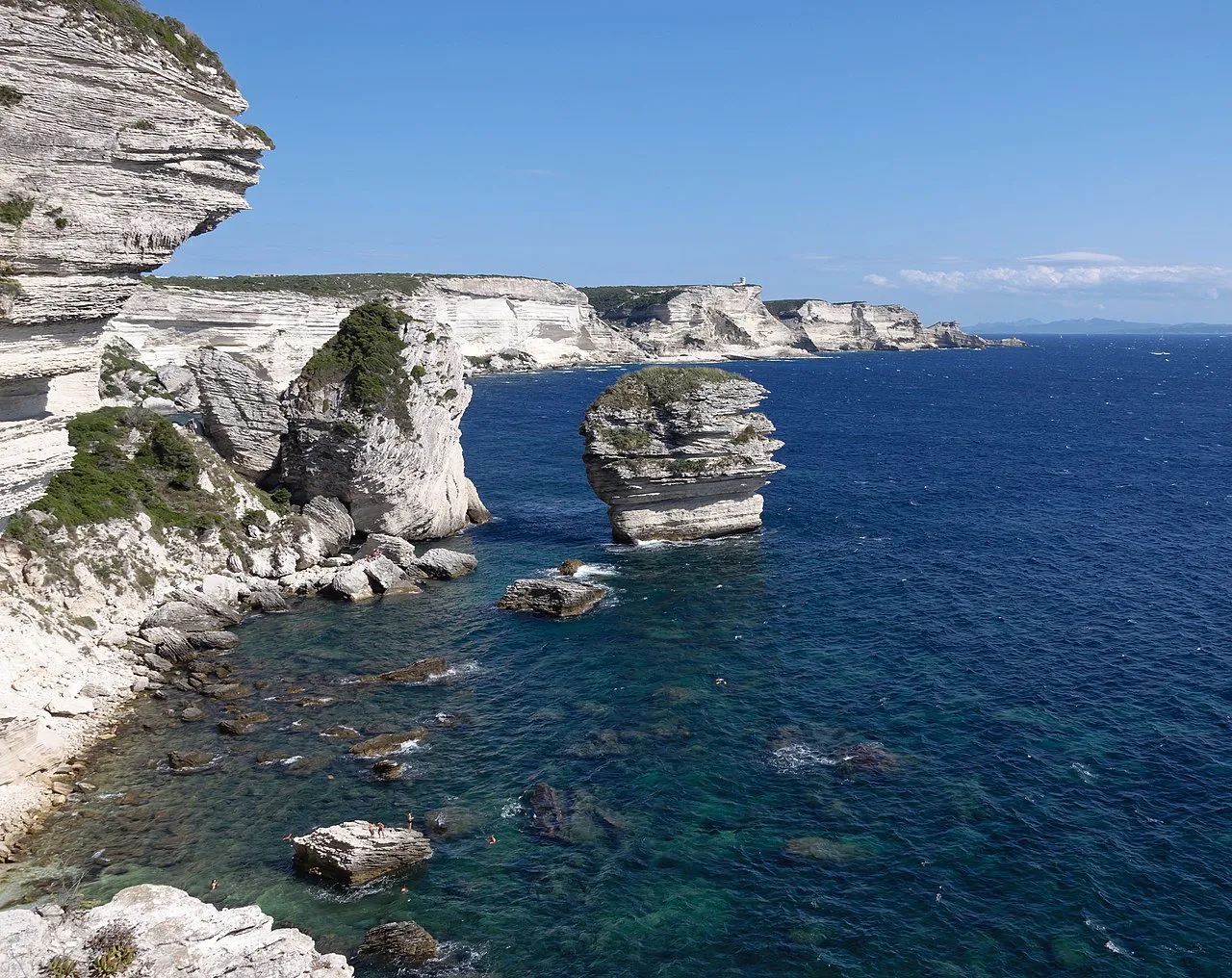 White limestone cliffs and the isolated Grain de Sable rock in clear blue water at Bonifacio