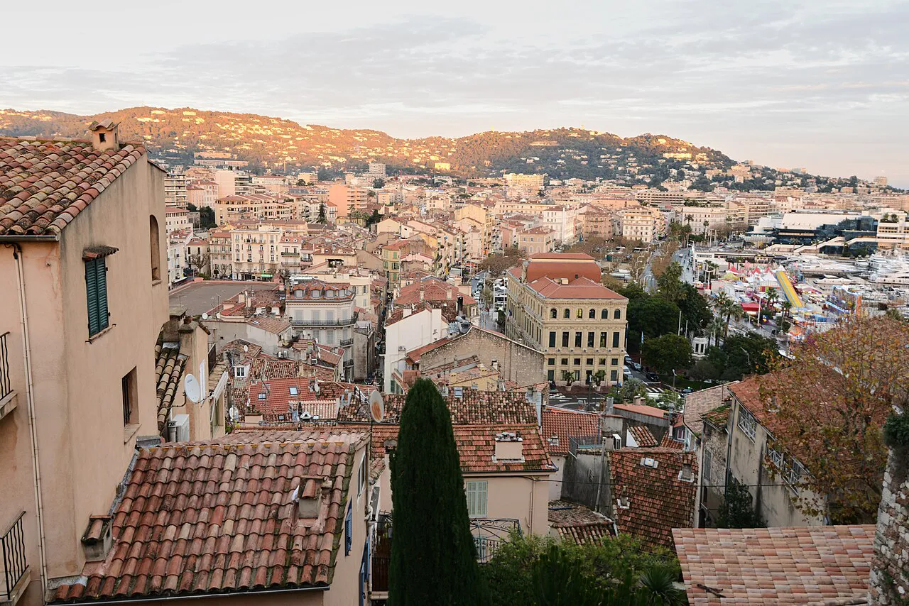 Terracotta rooftops of Cannes seen from the Le Suquet hill at dusk, with the hills behind