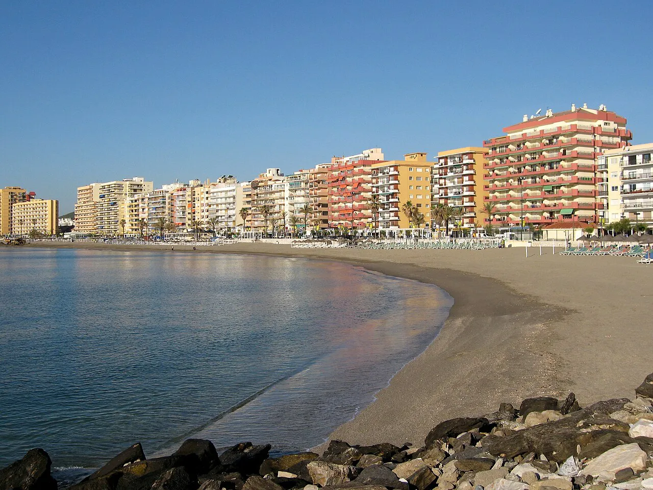 A curving sandy beach in Fuengirola backed by a line of seafront apartment blocks