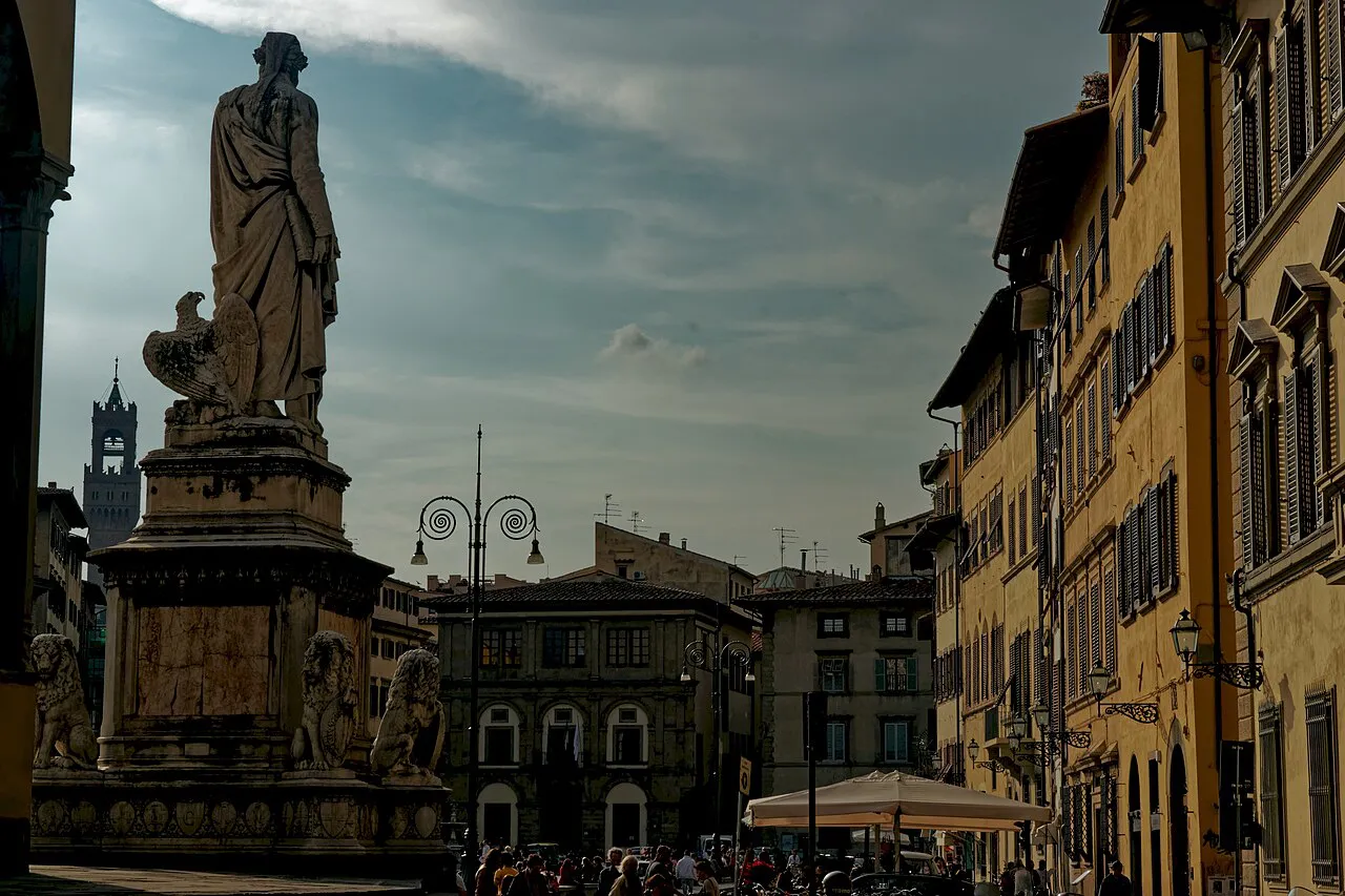 Dante Alighieri statue on Piazza Santa Croce in Florence, framed by tall palazzi