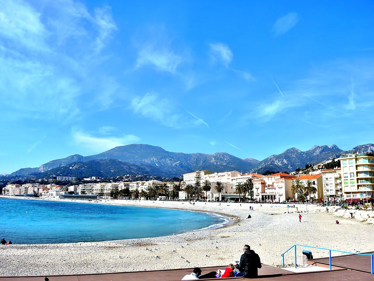Menton beach and the Promenade du Soleil curving below the mountains on a clear day