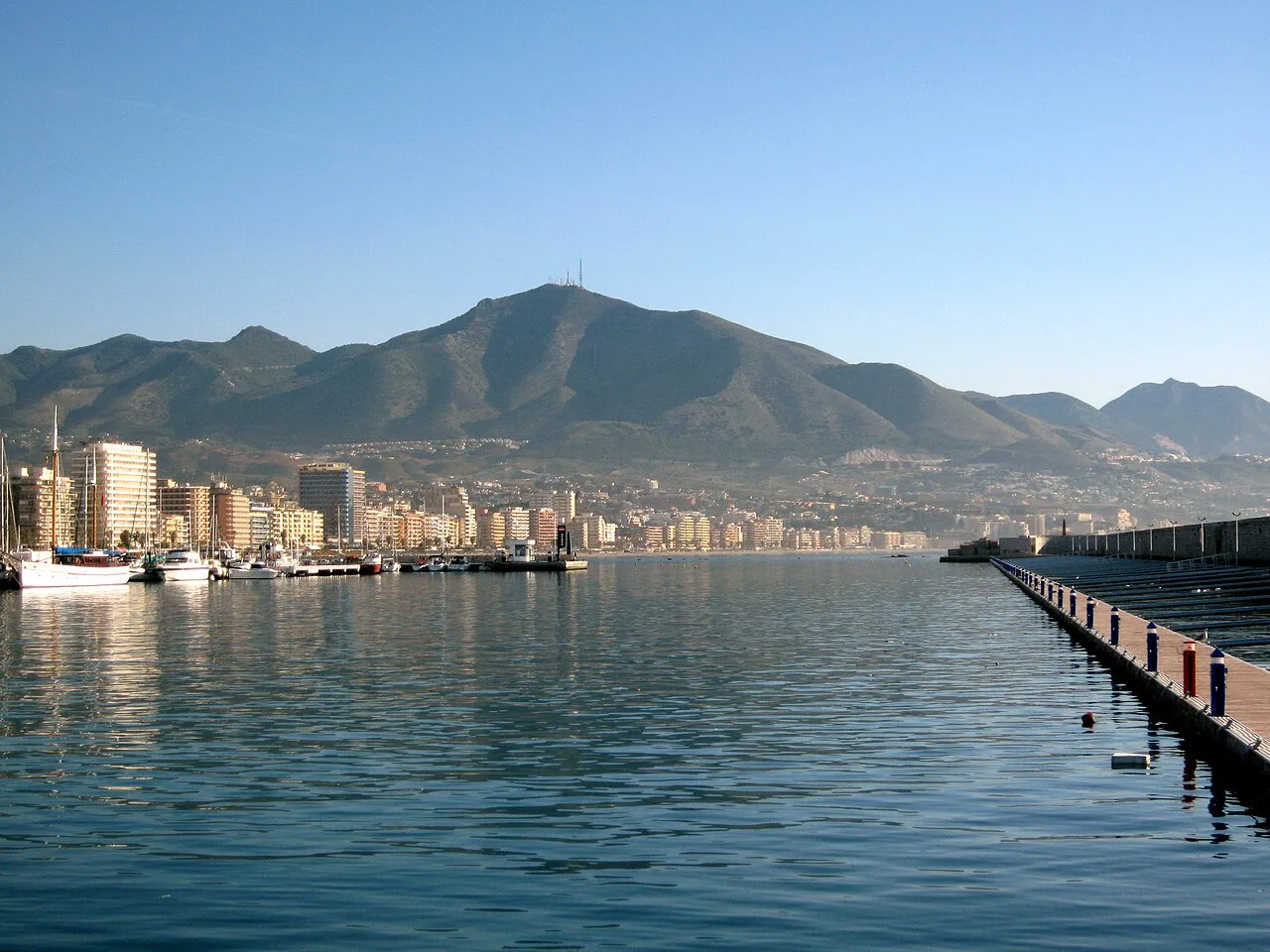 Fuengirola marina and seafront with the Sierra de Mijas mountains behind, seen across calm water