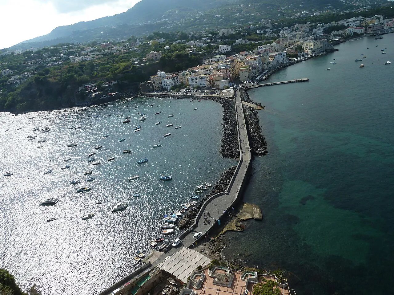 Aerial view of the stone causeway linking Ischia Ponte to the Aragonese Castle, with moored boats
