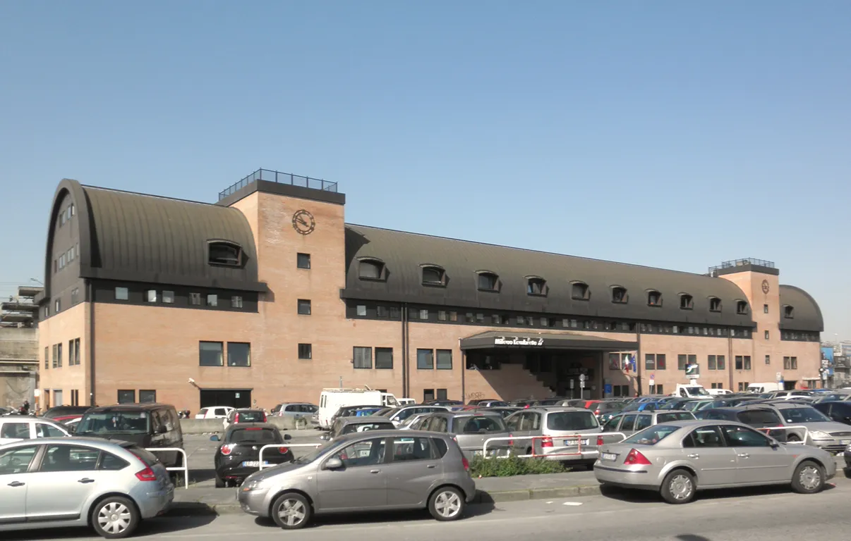Brick passenger building of Milano Lambrate railway station with cars parked in front